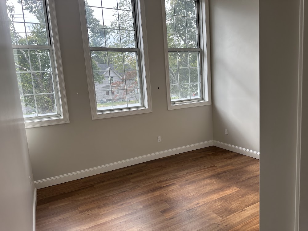 Interior room with three large windows and warm wood-look flooring